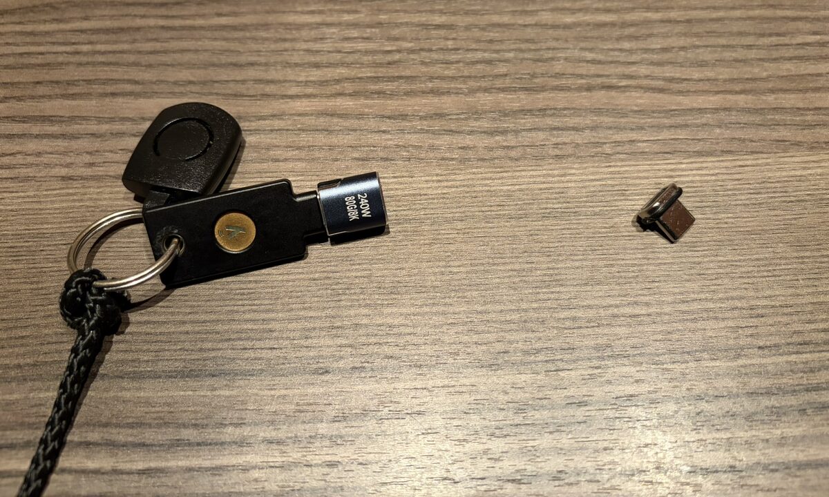 A YubiKey on a cord with the magnetic USB-C adapter on the key, and next to it the small half that stays in the laptop port
